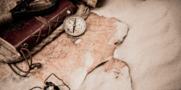 Mapa i kompas ilustrujące poszukiwanie pochodzenia nazwy Bełchatów.