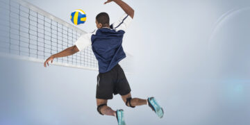 Mężczyzna w skoku wykonuje atak w meczu siatkówki.