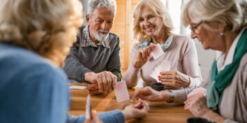 Uniwersytet Trzeciego Wieku w Bełchatowie - Twoja droga do aktywności i edukacji po 55 roku życia - Kultura Seniorzy z Uniwersytetu Trzeciego Wieku w Bełchatowie grają w karty podczas spotkania towarzyskiego.