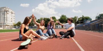 Wesoła młodzież siedzi na bieżni stadionu Szkoły Mistrzostwa Sportowego w Bełchatowie.